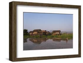 A man paddles his canoe past one of the floating villages on Inle Lake, Myanmar (Burma), Asia-Alex Treadway-Framed Photographic Print