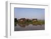 A man paddles his canoe past one of the floating villages on Inle Lake, Myanmar (Burma), Asia-Alex Treadway-Framed Photographic Print