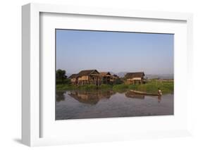 A man paddles his canoe past one of the floating villages on Inle Lake, Myanmar (Burma), Asia-Alex Treadway-Framed Photographic Print