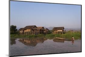 A man paddles his canoe past one of the floating villages on Inle Lake, Myanmar (Burma), Asia-Alex Treadway-Mounted Photographic Print