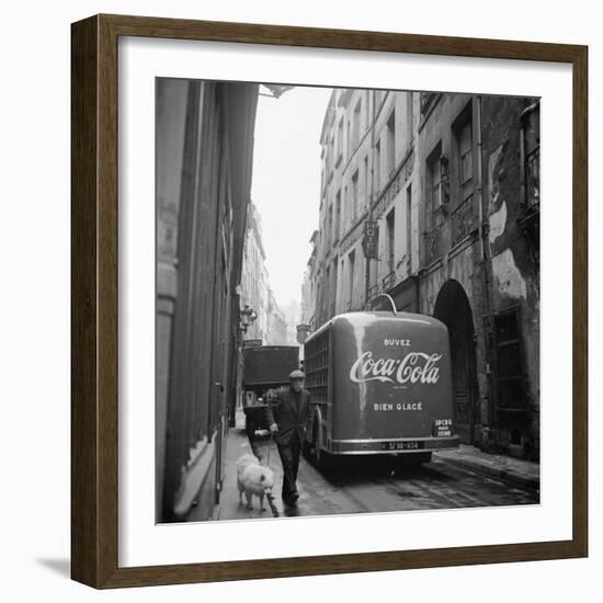 A Man Walks His Dog Beside a Bus with Coca Cola Advertisement, France, 1950-Mark Kauffman-Framed Photographic Print