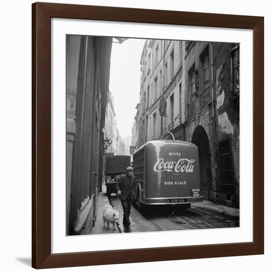 A Man Walks His Dog Beside a Bus with Coca Cola Advertisement, France, 1950-Mark Kauffman-Framed Photographic Print