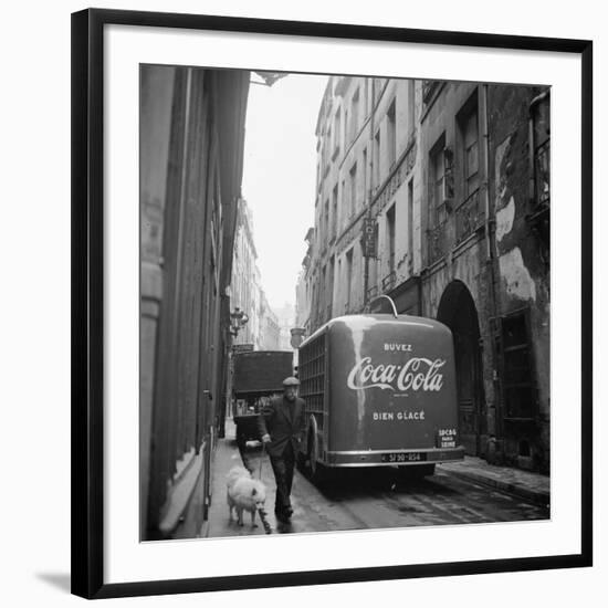 A Man Walks His Dog Beside a Bus with Coca Cola Advertisement, France, 1950-Mark Kauffman-Framed Photographic Print