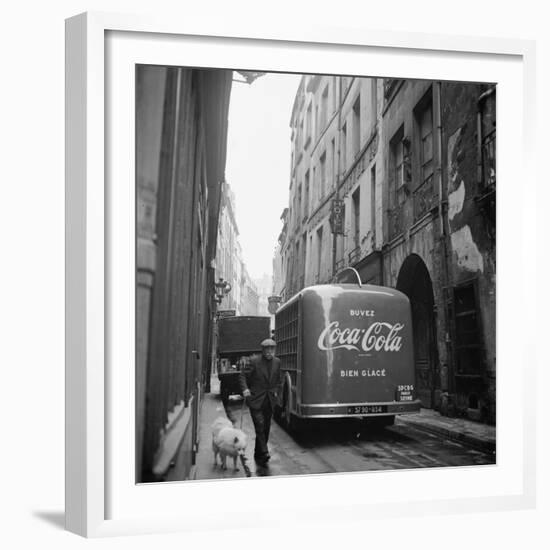 A Man Walks His Dog Beside a Bus with Coca Cola Advertisement, France, 1950-Mark Kauffman-Framed Photographic Print