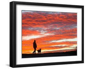 A Man Walks His Dog Under a Red Sky-null-Framed Photographic Print