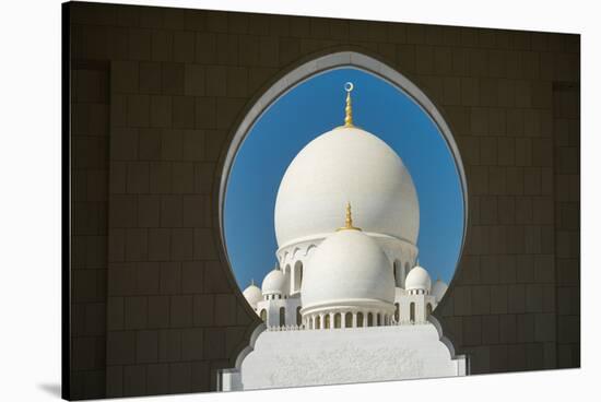 A mosque is framed by an arched passageway in Abu Dhabi, United Arab Emirates, Middle East-Logan Brown-Stretched Canvas