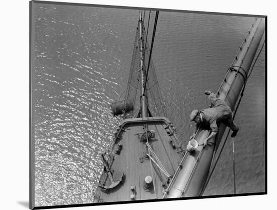 A Painter Lays Across the Rigging While Painting on Sailing Ship-null-Mounted Photographic Print