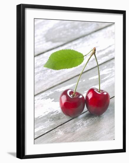 A Pair of Cherries with a Leaf on a Wooden Table-Jürgen Klemme-Framed Photographic Print