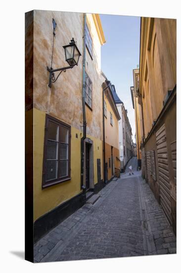 A pedestrian walks the streets of Stockholm's colorful and historic Gamla Stan district, Stockholm,-Jon Reaves-Stretched Canvas