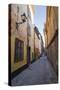 A pedestrian walks the streets of Stockholm's colorful and historic Gamla Stan district, Stockholm,-Jon Reaves-Stretched Canvas