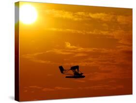 A Pilot Flies a Small Plane Past the Setting Sun Over Lake Winnipesaukee-null-Stretched Canvas