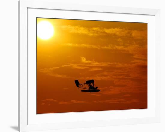 A Pilot Flies a Small Plane Past the Setting Sun Over Lake Winnipesaukee-null-Framed Photographic Print