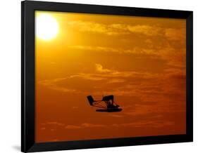 A Pilot Flies a Small Plane Past the Setting Sun Over Lake Winnipesaukee-null-Framed Photographic Print