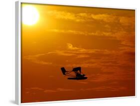 A Pilot Flies a Small Plane Past the Setting Sun Over Lake Winnipesaukee-null-Framed Photographic Print