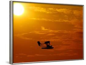 A Pilot Flies a Small Plane Past the Setting Sun Over Lake Winnipesaukee-null-Framed Photographic Print