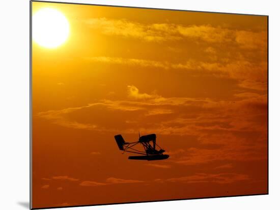 A Pilot Flies a Small Plane Past the Setting Sun Over Lake Winnipesaukee-null-Mounted Photographic Print