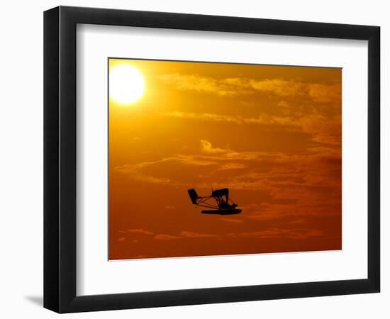 A Pilot Flies a Small Plane Past the Setting Sun Over Lake Winnipesaukee-null-Framed Photographic Print