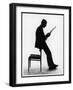 A Silhouette of a Businessman Leaning Against a Chair Reading a Newspaper-null-Framed Photographic Print