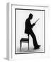 A Silhouette of a Businessman Leaning Against a Chair Reading a Newspaper-null-Framed Photographic Print