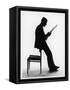 A Silhouette of a Businessman Leaning Against a Chair Reading a Newspaper-null-Framed Stretched Canvas