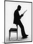 A Silhouette of a Businessman Leaning Against a Chair Reading a Newspaper-null-Mounted Photographic Print