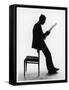A Silhouette of a Businessman Leaning Against a Chair Reading a Newspaper-null-Framed Stretched Canvas