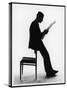 A Silhouette of a Businessman Leaning Against a Chair Reading a Newspaper-null-Stretched Canvas