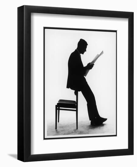 A Silhouette of a Businessman Leaning Against a Chair Reading a Newspaper-null-Framed Premium Photographic Print