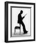 A Silhouette of a Businessman Leaning Against a Chair Reading a Newspaper-null-Framed Premium Photographic Print