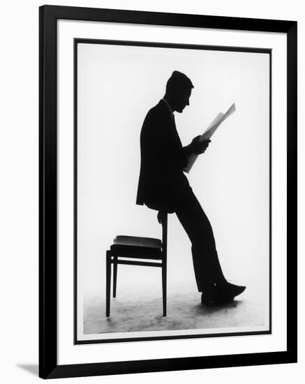 A Silhouette of a Businessman Leaning Against a Chair Reading a Newspaper-null-Framed Photographic Print