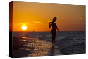 A Silhouette of a Woman Wearing a Hat Walking in the Surf at Sunset on Holbox Island, Mexico-Karine Aigner-Stretched Canvas