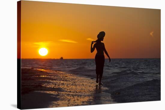 A Silhouette of a Woman Wearing a Hat Walking in the Surf at Sunset on Holbox Island, Mexico-Karine Aigner-Stretched Canvas