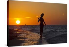 A Silhouette of a Woman Wearing a Hat Walking in the Surf at Sunset on Holbox Island, Mexico-Karine Aigner-Stretched Canvas