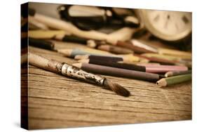 A Stained Brush, Colored Pencils of Different Colors, a Pair of Eyeglasses and an Old Clock on a Ta-nito-Stretched Canvas