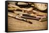 A Stained Brush, Colored Pencils of Different Colors, a Pair of Eyeglasses and an Old Clock on a Ta-nito-Framed Stretched Canvas