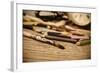 A Stained Brush, Colored Pencils of Different Colors, a Pair of Eyeglasses and an Old Clock on a Ta-nito-Framed Photographic Print