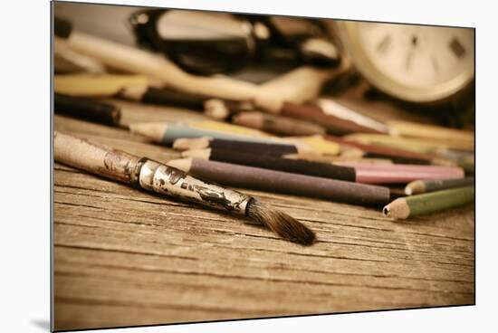 A Stained Brush, Colored Pencils of Different Colors, a Pair of Eyeglasses and an Old Clock on a Ta-nito-Mounted Photographic Print