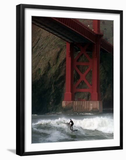 A Surfer is Dwarfed by the Northern End of the Golden Gate Bridge While Riding the Waves-null-Framed Premium Photographic Print