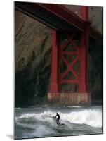 A Surfer is Dwarfed by the Northern End of the Golden Gate Bridge While Riding the Waves-null-Mounted Premium Photographic Print