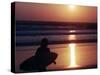 A Surfer is Silhouetted by the Setting Sun as He Leaves the Pacific Ocean on Venice Beach-null-Stretched Canvas