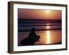 A Surfer is Silhouetted by the Setting Sun as He Leaves the Pacific Ocean on Venice Beach-null-Framed Photographic Print