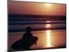 A Surfer is Silhouetted by the Setting Sun as He Leaves the Pacific Ocean on Venice Beach-null-Mounted Photographic Print