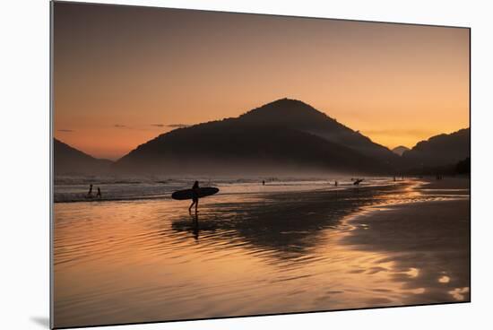 A Surfer Makes His Way Out of the Water at Sunset on Praia Do Itamambuca in Brazil-Alex Saberi-Mounted Photographic Print