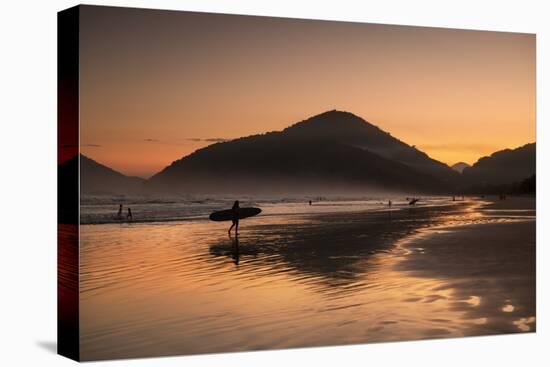 A Surfer Makes His Way Out of the Water at Sunset on Praia Do Itamambuca in Brazil-Alex Saberi-Stretched Canvas