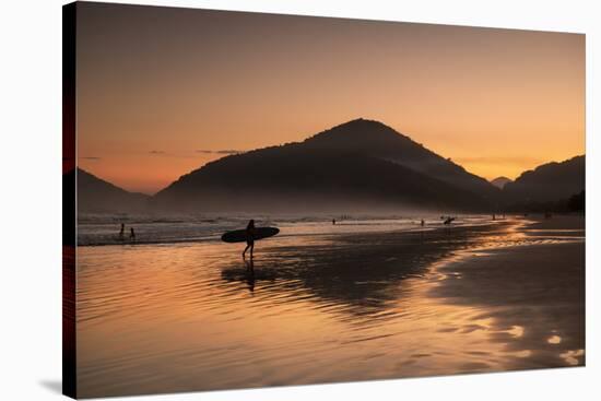 A Surfer Makes His Way Out of the Water at Sunset on Praia Do Itamambuca in Brazil-Alex Saberi-Stretched Canvas