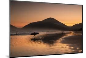 A Surfer Makes His Way Out of the Water at Sunset on Praia Do Itamambuca in Brazil-Alex Saberi-Mounted Photographic Print