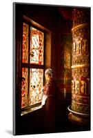 A Tibetan woman stands next to a large prayer wheel of the temple of Boudhanath Stupa, Kathmandu, N-Julian Bound-Mounted Photographic Print