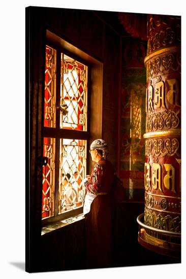 A Tibetan woman stands next to a large prayer wheel of the temple of Boudhanath Stupa, Kathmandu, N-Julian Bound-Stretched Canvas