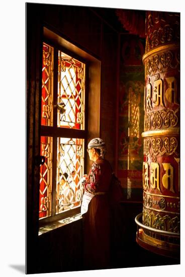 A Tibetan woman stands next to a large prayer wheel of the temple of Boudhanath Stupa, Kathmandu, N-Julian Bound-Mounted Premium Photographic Print