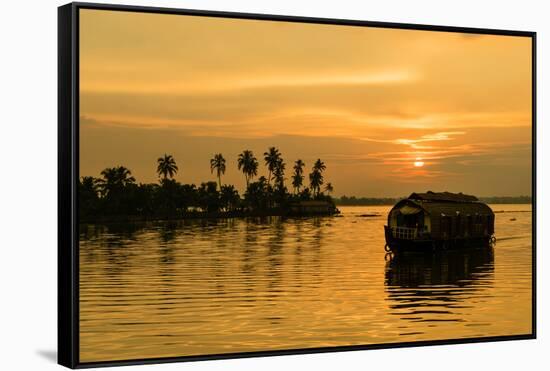 A traditional houseboat moves past the setting sun on the Kerala Backwaters, Kerala, India, Asia-Logan Brown-Framed Stretched Canvas
